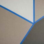 Beżowa i szara ściana z geometrycznymi wzorami oddzielonymi niebieskimi liniami