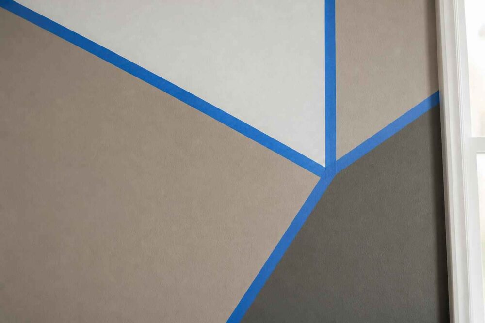 Beżowa i szara ściana z geometrycznymi wzorami oddzielonymi niebieskimi liniami